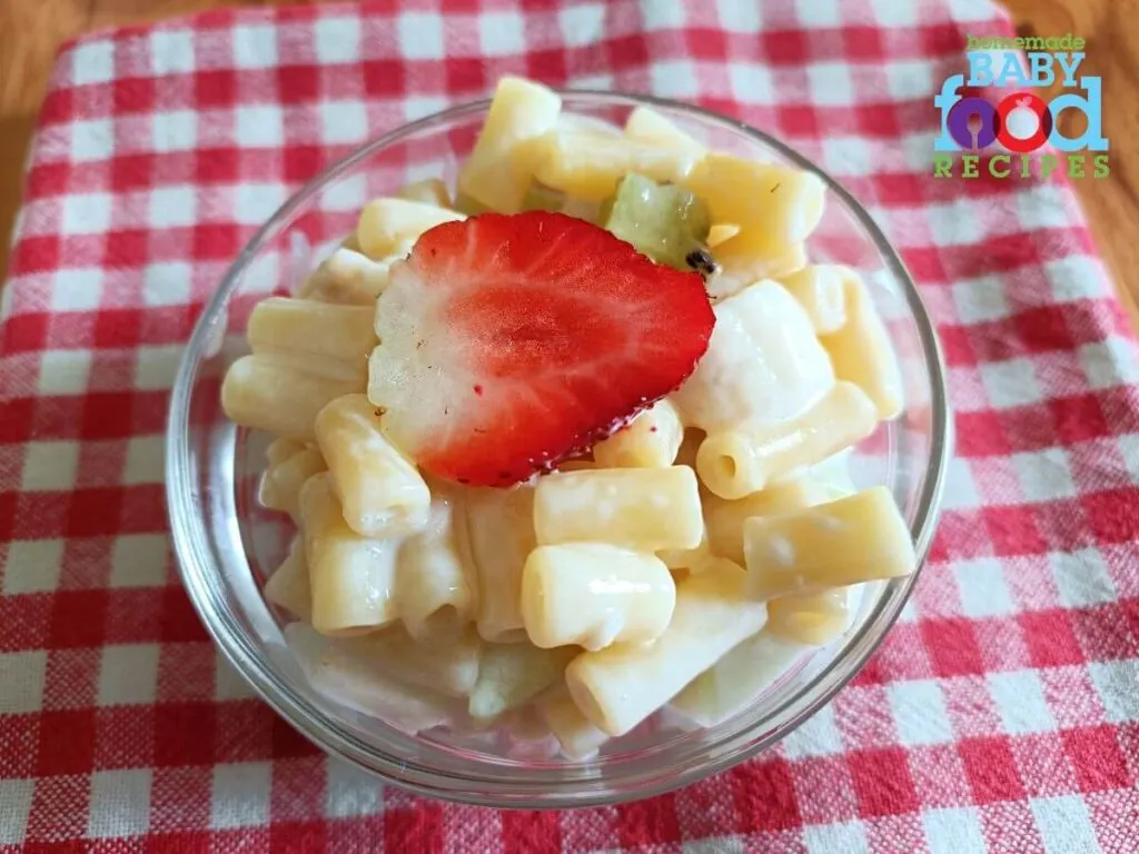 A bowl of fruit salad for baby topped with a strawberry