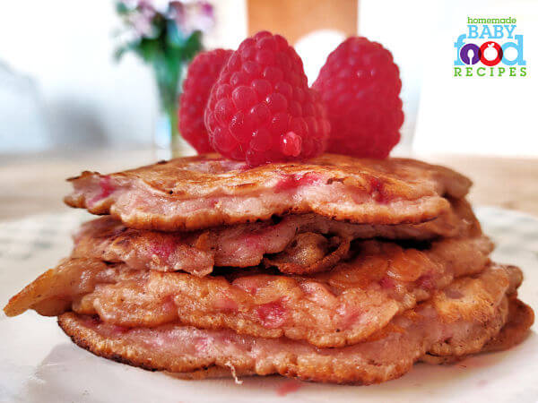 A stack of raspberry pancakes topped with fresh raspberries