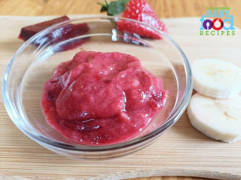 A bowl of baby food made with mashed strawberry, banana, and beet